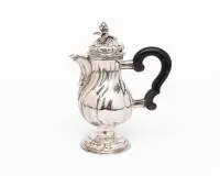 Petite cafetière en argent, Guttstadt (Prusse-Orientale), vers 1750, argent repoussé et fondu ; corps piriforme à godrons multiples sur pied rond profilé et galbé, col élevé avec bec court et incurvé ; couvercle bombé à charnière avec décor de godrons et bouton floral et feuillagé en relief ; poignée latérale en bois noirci avec montures en argent incurvées, H. 16 cm, env. 205 g