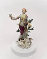 Figurka porcelanowa, "Pasterz z ptakiem", Miśnia, znak skrzyżowanych mieczy, prawdopodobnie lata 80., 1. wybór, numer modelu 61079, polichromowana i złocona, projekt modelu Johanna Joachima Kändlera (1706-1775), 26,5 cm wysokości, kłos przyklejony, brakujące liście