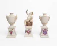 3 pièces en porcelaine blanche, Nymphenburg, 2 petits vases amphores avec anses de satyre ainsi qu'un petit Bacchus sur tonnelet sur piédestal avec cartouche armoriée, env. 15 cm et 18,5 cm de haut