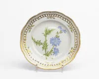Royal Copenhagen, Flora Danica, assiette ajourée, Copenhague, 1979-1984, numéro de modèle 3553, décor polychrome et riche dorure, aile ajourée avec bord dentelé, au centre représentation de la Chicorée sauvage (Chiorium Intybus L.), au revers...