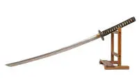 Katana en Koshirae, Japon, probablement 19e s. ou plus ancien, lame en acier légèrement courbée à un tranchant, forme shinogi-zukuri, surface avec structure de soudure damassée/hada, habaki cuivré, tsuba mokkō simple en fer patiné avec deux ouvertures latérales. Poignée en bois avec samegawa (peau de raie) et tsukamaki textile noir ; garnitures métalliques patinées à décor figuratif en relief, saya en bois laqué noir avec garnitures métalliques ornementées, dont une garniture terminale en relief