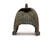 Casque en bronze, probablement Chine ou espace culturel nord-chinois et intérieur asiatique, possiblement époque Zhou à Han, 1er millénaire av. J.-C. à 1er millénaire apr. J.-C., alliage de cuivre, probablement bronze, coulé ; cloche de casque haute, presque hémisphérique avec nervures radiales marquées et solide ornement sommital rectangulaire ajouré, probablement pour recevoir un décor de casque autrefois présent ; dans la partie inférieure, champs en arc des deux côtés ainsi qu'une rangée cir