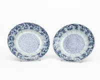 Paire d'assiettes, Chine, période Kangxi (1662-1722), porcelaine bleu sous couverte, rosette florale stylisée avec ornements foliaires au centre, large aile avec cartouches alternés à décor floral et bord lobé, au revers double cercle avec...