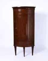 Armoire d'angle classique, 1ère moitié 19e s., placage acajou, corps quart de cylindre sur hauts pieds coniques, incrustations, trois tablettes, H. 169.5 cm, côté 54.5 cm