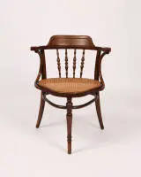 Schrijfarmstoel, Jacob & Josef Kohn, Wenen, rond 1900, gebogen eikenhout, zitting met Weense rieten vlecht, corpus met armleuningen, rugleuning met balusters, origineel fabrieksetiket en sjabloon aan onderzijde, h. 82 cm, zitting met geringe...
