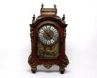 Duży zegar Boulle, Ludwik XIV, Francja, ok. 1700, obudowa przeszklona z trzech stron w markieterii Boulle, bogate brązowe aplikacje, m.in. figuralne maskarony na czterech narożnikach oraz woluty akantowe i ozdobne wazy, tarcza z niebieskimi emaliowanymi kartuszami cyfrowymi wokół centralnego medalionu portretowego z profilem Ludwika XIV, poniżej alegoryczne reliefowe przedstawienie Apollina na rydwanie (= Król Słońce), wahadło z zawieszeniem na nici, bicie półgodzinne na dzwonku, mechanizm dział
