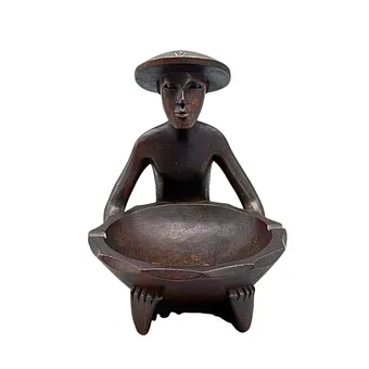 ASCHENBECHER AUS HOLZ MIT EINEM SITZENDEN ASIATISCHEN MANN.