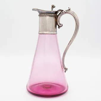 ANTIKE WEINKARAFFE, UM 1900 HERGESTELLT, CLARET JUG, FARBIGES CRANBERRY-GLAS, OBERE TEIL UND DER GRIFF AUS VERSILBERTEM METALL.