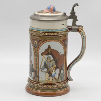 VILLEROY & BOCH METTLACH, KERAMICKÝ DŽBÁN; CÍNOVÉ VÍKO S DEDIKACÍ Z ROKU 1892, MOTIV 3X ŽOKEJ S KONĚM, MODEL 1733, RELIÉF A ZLACENÍ, NĚMECKO.