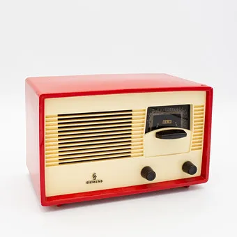 HISTORIC SIEMENS TUBE TABLE RADIO, MODEL SIEMENS SUPER A 60, 1950S, RED PLASTIC CASE WITH IVORY FRONT PANEL, SPEAKER GRILLE AND BLACK KNOBS.
