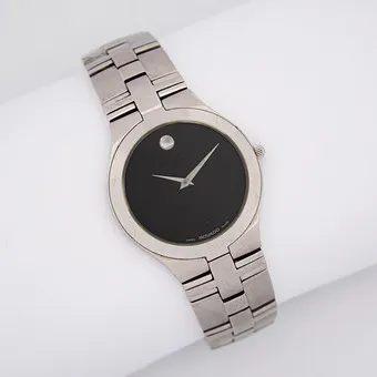 MOCADO JURO WRISTWATCH, QUARTZ MOVEMENT, STAINLESS STEEL WITH A CHARACTERISTIC BLACK DIAL, SCRATCH-RESISTANT SAPPHIRE GLASS, WATER-RESISTANT UP TO 30 METERS, SILVER-COLORED HOUR MARKER AT 12 O'CLOCK, STAINLESS STEEL BRACELET.