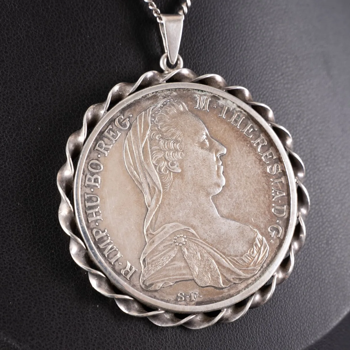 Silberner Maria-Theresia-Taler als Kettenanhänger gefasst, an ca. 72 cm langer Gliederkette. Kette und Fassung aus 835er…