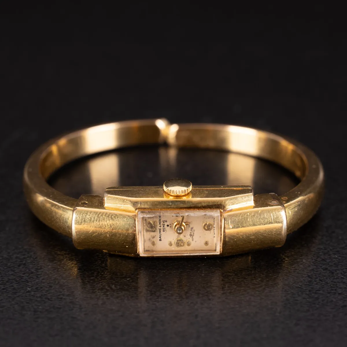 Petite montre bijou de qualité sur bracelet ouvert, finition dorée lisse, épaisseur de bras variable.