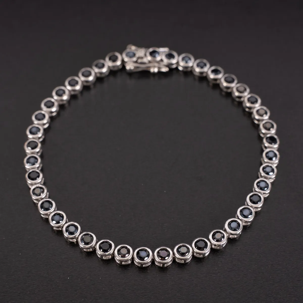 Bracelet tennis en argent 925, serti de 41 pierres rondes vert foncé taillées. Fermoir à boîte avec 2 sécurités