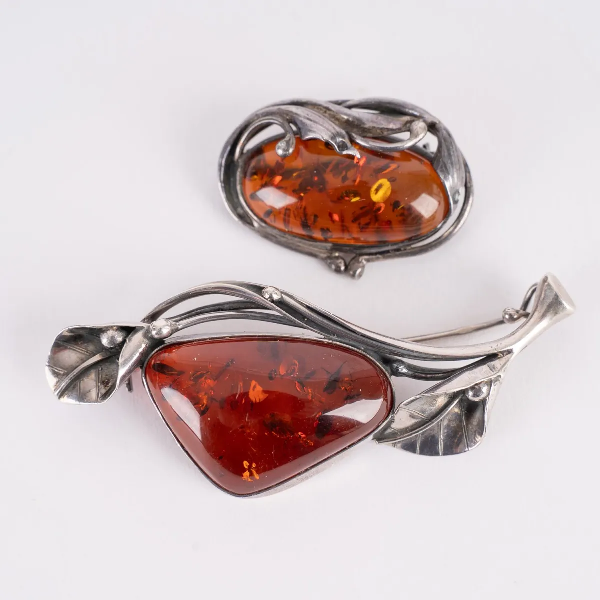 2 Broschen, Silber, Bernstein, Länge zwischen ca. 6,5 und 3 cm. Schöner Erhalt.
