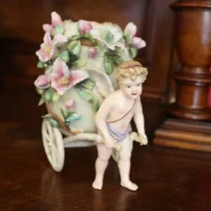 Putte mit Porzellan Ei auf Wagen, H 16cm, gemarkt