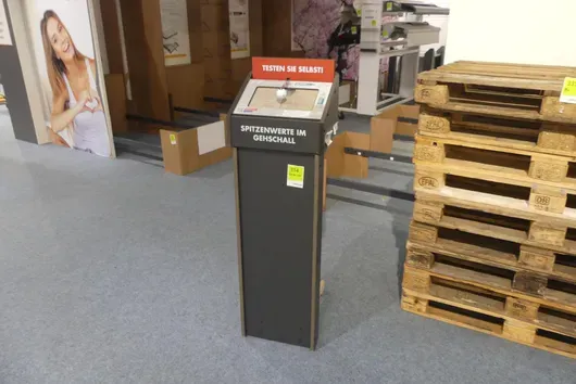 Presentation display column "Test it yourself! – Top values in footfall sound" for floor coverings, with test device