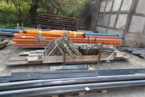 Lot of formwork and scaffolding accessories, including pipes and formwork clamps, on stacking rack