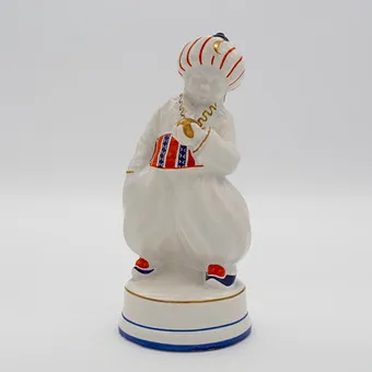 OSKAR BURKHARDT. ORIENTALISCHE FIGUR „TÜRKE“, ERNST TEICHERT GMBH (AUCH BEKANNT ALS TEIL DER MEISSNER OFEN- UND PORZELLANFABRIK VORM. CARL TEICHERT), JUNGE IN ORIENTALISCHER KLEIDUNG, STEINGUT, GLASIERT, POLYCHROM VON HAND STAFFIERT, PARTIELL MIT GOLDDEKOR, UM 1910.
