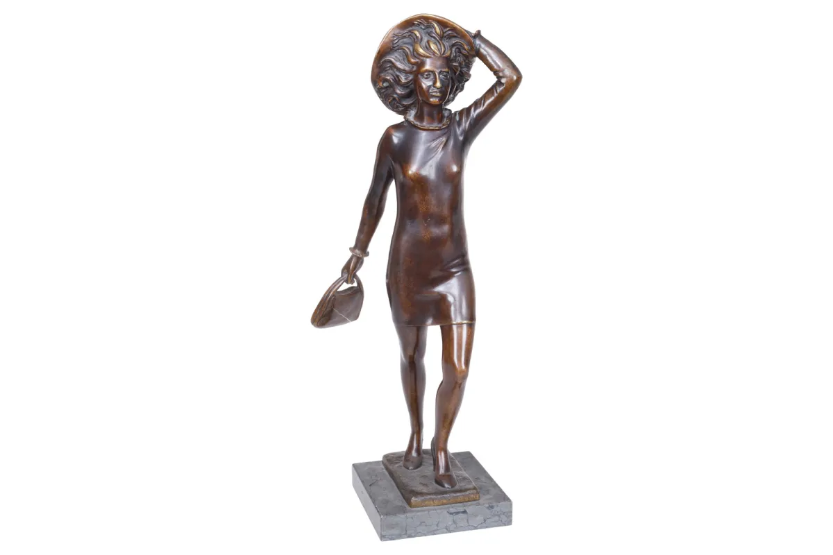 Bronzen beeldje van een meisje met hoed en handtas in de wind