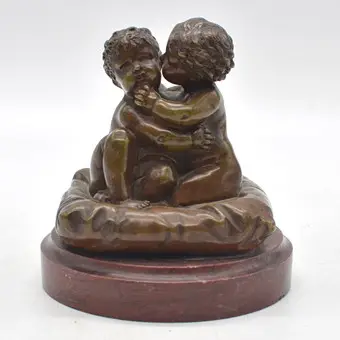 LOUIS KLEY (1833-1911). To omfavnende børn på en pude, skulptur i bronze med stensokkel i rød, omkring 1900, Frankrig, med signatur.