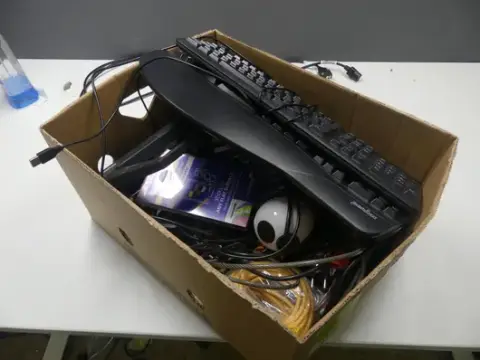 Konvolut tilbehør, bl.a. tastaturer, webcam, kabellås, netværkskabel, monitorfod, kabler