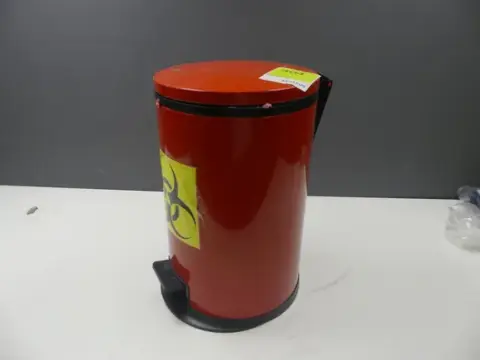 Pattumiera a pedale rossa con adesivo biohazard, con contenuto