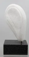 白色大理石抽象雕塑,垂直安装在深色方形花岗岩底座上。有HJA字母组合标记
