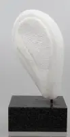 abstrakt skulptur af hvid marmor monteret lodret på en mørk, firkantet granitsokkel. Monogrammeret HJA
