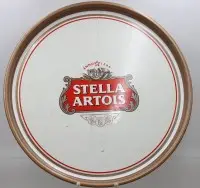 Vintage metal-serveringsbakke fra bryggeriet Stella Artois med hvid overflade, rødt og gyldent logo samt gylden kant