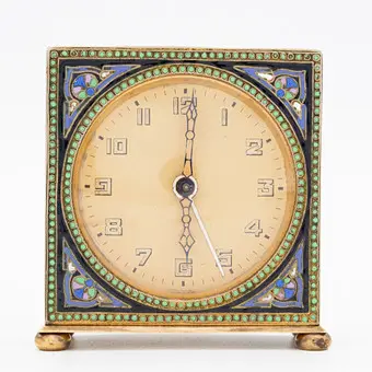 ANTIK ART DÉCO VÆKKEUR (CA. 1920–1930), KIENZLE, FORGYLDT MESSING, DEKORERET MED POLYKROM CHAMPLEVÉ-EMALJE, MEKANISK 36-TIMERS VÆRK MED HÅNDOPTRÆK OG INTEGRERET VÆKKEURSFUNKTION.
