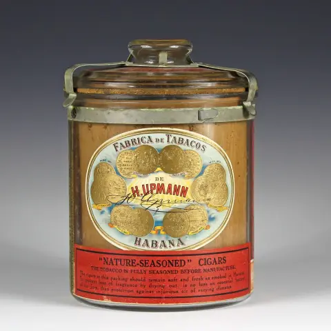 Reklame – En humidor fra H. Upmann, Havanna. Cuba, omkring 1930, glashumidor med producentetikette "Fabrica de Tabacos de H. Upmann Habana, nature.seasoned Cigars". Højde: ca. 21 cm.