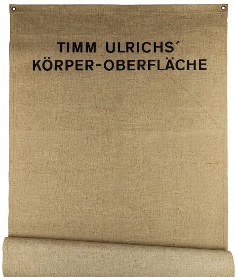 Fluxus – Ulrichs, Timm. Selbstporträt. Lichaamskunstobject. Zeefdruk op juteweefsel met messing ogen.