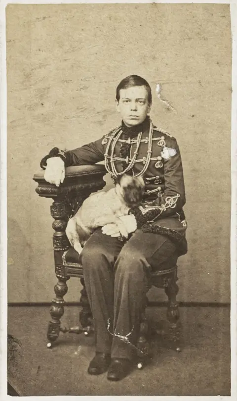 Dinastija Romanov – carević Aleksandr Aleksandrovič Ruski (kasnije okrunjen kao Aleksandar III.) kao mladić u uniformi husarske pukovnije tjelesne garde, s malim psom u krilu