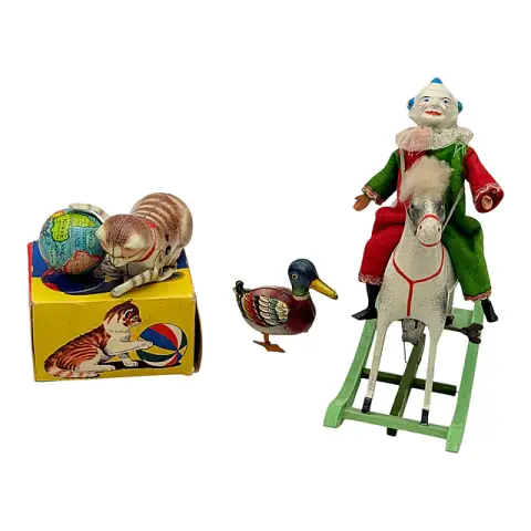 Trois jouets à remonter, chat Köhler avec globe dans la boîte, canard en tôle, clown sur cheval à bascule