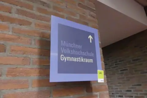 Indicator/panou de semnalizare „Münchner Volkshochschule Gymnastikraum”, albastru, cu suport de perete