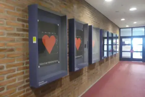 7 db fali vitrin/hirdetőtábla üveg előlappal, kék, „Münchner Volkshochschule” felirattal, kulcs nélkül