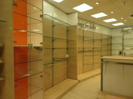 1 wall-mounted shelving system, approx. 3 m x 20 linear m, with maple wood back panel, various hanging systems, chrome design and glass shelves, with 1 illuminated advertising shelf, 1 2-part shelf unit beech wood, white back panel, 1 display cabinet 8 glass shelves illuminated lockable, 3 display platforms geometric shapes maple wood and 1 window display unit white back panel, 2 glass shelves and 2 white cubes
