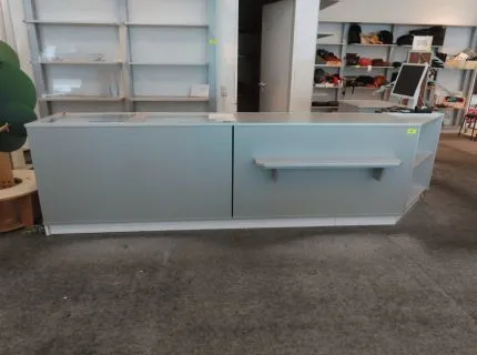 1 Eck-Verkaufstresen, ca. 1,50 m x 3,50 m, im rückwärtigen Bereich mit Ablagen, 1 Auszug und 1 Flügeltür, sowie 2 Schubladenvitrinen mit Glasplatte, grau