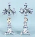Paire de bougeoirs – porcelaine, peint à la main, riche décor avec fleurs en relief, base sur 3 pieds courbés, tiges figuratives avec...