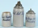Chopes à bière, 3 pièces – chopes de cantine – grès, chacune avec désignation de régiment émaillée bleu, 2 avec couvercles en étain, 1 avec fusée d'obus montée, H= 13-23 cm, vers 1900, 2 avec fêlure sur la paroi