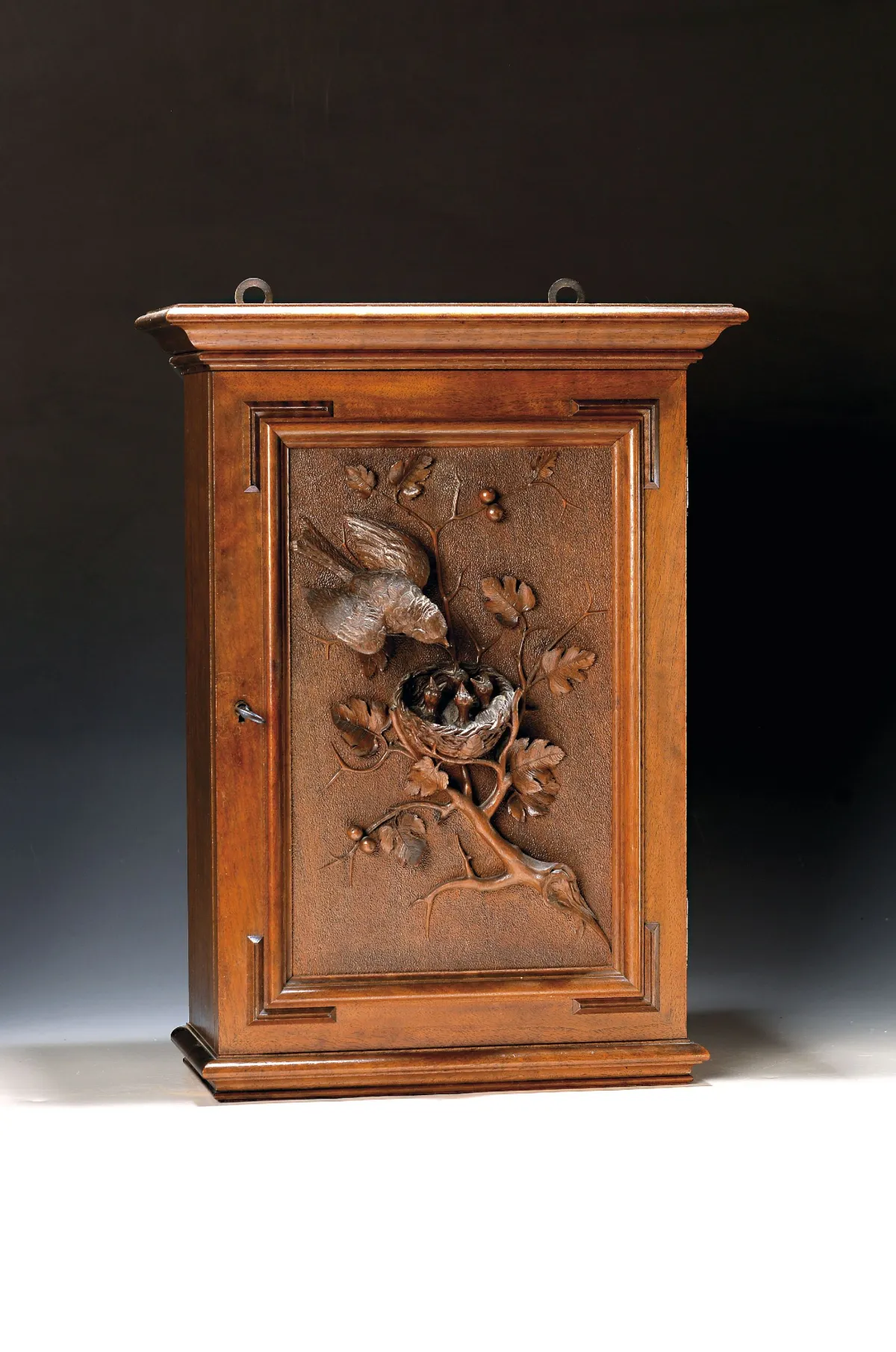 Small wall cabinet, German, circa 1890-1900, walnut, door panel richly carved in full relief