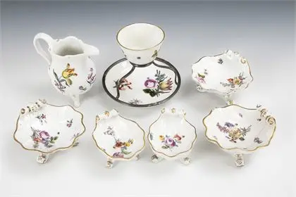 7 barokke porseleinen: 5 schelpenschoteltjes, melkkan en kopje met schotel en zilvermontuur. Meissen