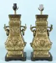Paire de lampes de table – fonte de laiton, décor en relief, base en bois, corps balustre avec 2 poignées, 1 douille, H= 58 cm
