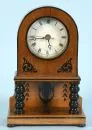 Table clock – wooden case partly ebonized, black decorations, 2 turned columns, glazed dial, Roman numerals, H= 27 cm
