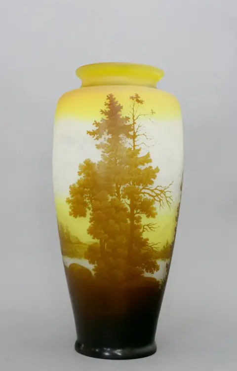 Vase, Emile Gallé, Nancy, France, vers 1905. Verre blanc laiteux, en partie légèrement jaunâtre, avec décor d'un paysage de montagne et de grands arbres. Sur/sous-couche de différentes couleurs. H 45 cm. Sur la panse, signé en haut-relief "Gallé".