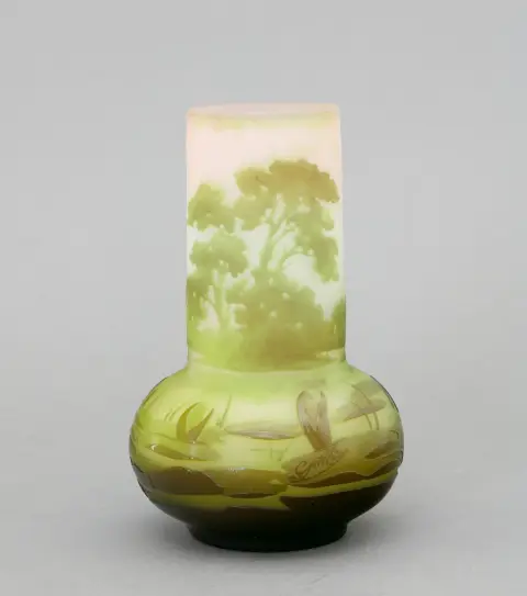 Vase, Emile Gallé, Nancy, France, vers 1905. Forme balustre avec col conique. Verre laiteux incolore, sous/sur-couche de différentes couleurs avec paysage de rive gravé en relief avec plantes aquatiques, arbres en arrière-plan. H 15,2 cm. Sur la panse bombée, signé "Gallé".