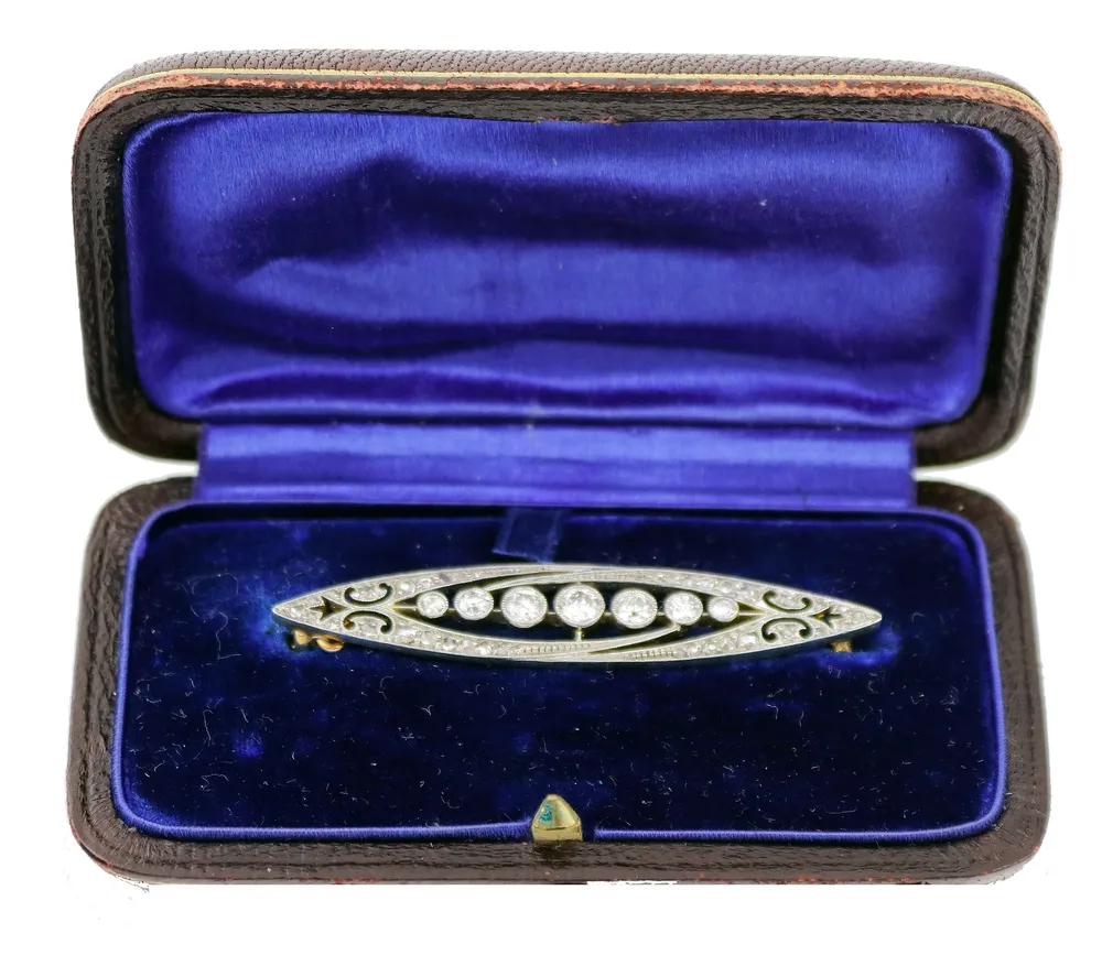 Broche, or gris 585, partiellement rhodié, forme de navette Art déco, sertie de 7 petits diamants taille brillant de 0,03 à 0,17 ct.