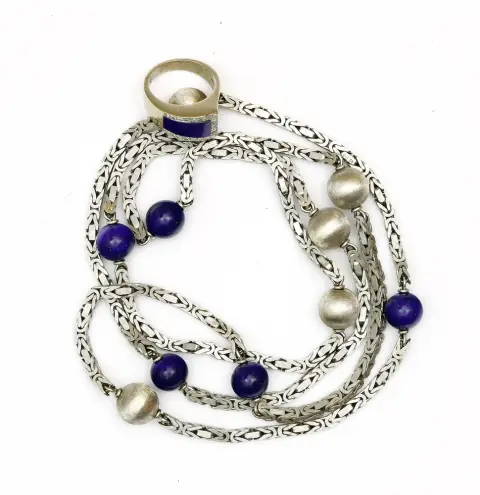 Collier et bague avec lapis-lazuli, or blanc 585. Bague avec lapis entouré de petits diamants 0,23 ct. Taille 52/53. Poids 10,56 g. - Collier avec 5 boules de lapis. L env. 88 cm, poids brut 84,8 g.