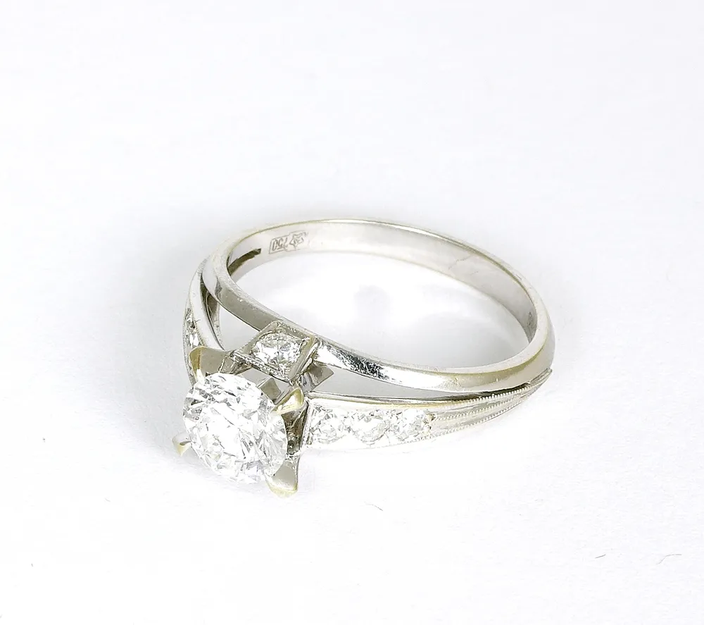 Ring, 750er WG. mit Diamant im Brillantschliff von ca. 0,80 ct. Krabbenhalterung, Top Wesselton, LC. mit acht begleitenden kleinen…